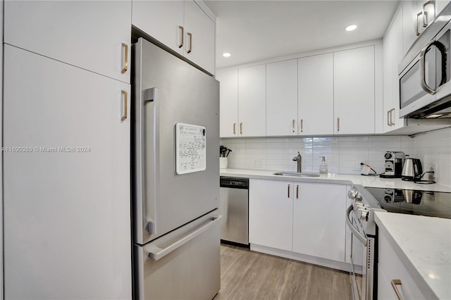 kitchen featuring appliances with stainless steel finishes, sink, light hardwood / wood-style floors, and white cabinets