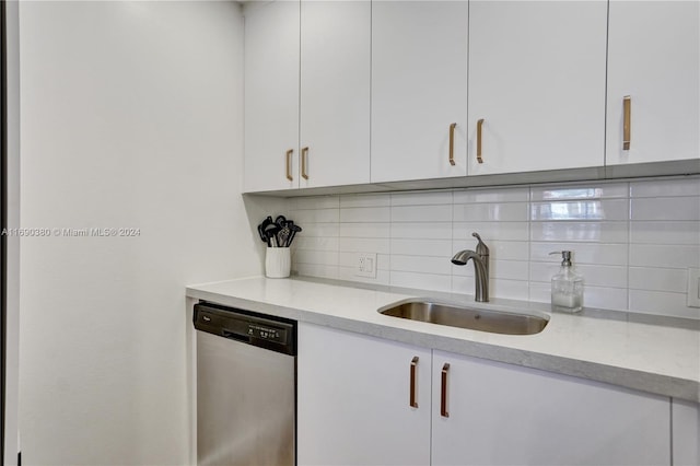 kitchen featuring decorative backsplash, sink, stainless steel dishwasher, light stone countertops, and white cabinetry