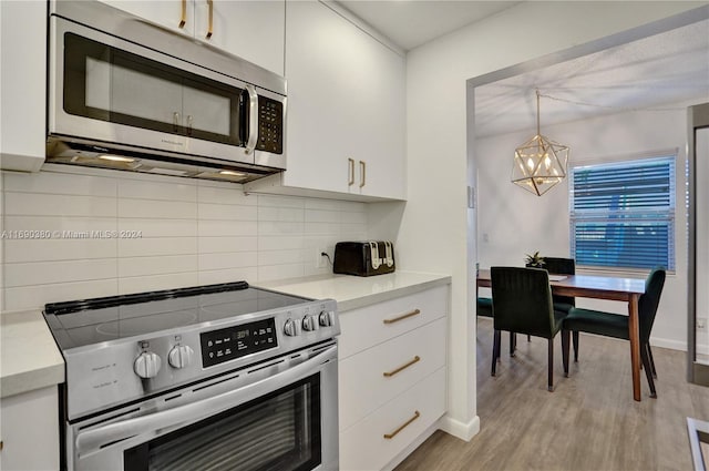 kitchen featuring stainless steel appliances, white cabinets, tasteful backsplash, pendant lighting, and light wood-type flooring