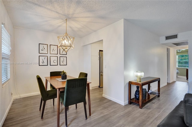 dining area featuring hardwood / wood-style flooring, a chandelier, and a textured ceiling