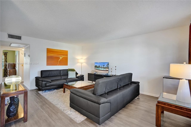 living room featuring light hardwood / wood-style flooring and a textured ceiling