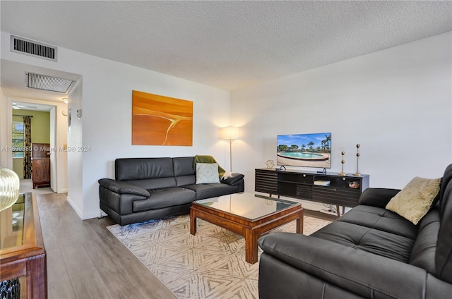 living room featuring light wood-type flooring and a textured ceiling