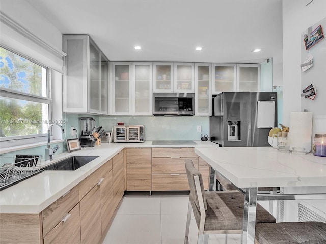 kitchen with a kitchen bar, appliances with stainless steel finishes, sink, light brown cabinets, and light tile patterned flooring