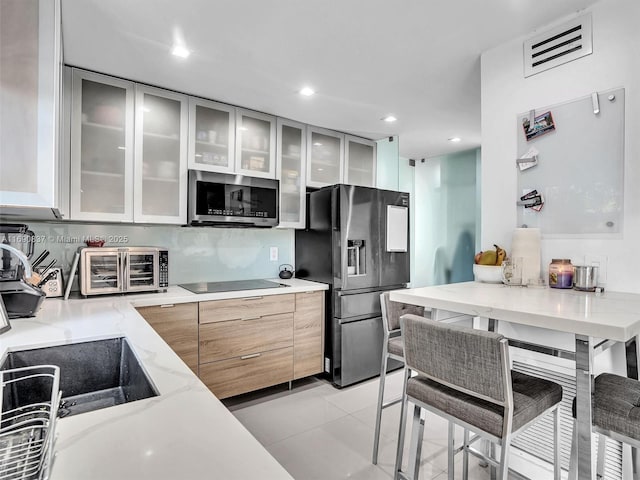 kitchen featuring light tile patterned flooring, decorative backsplash, sink, and black appliances