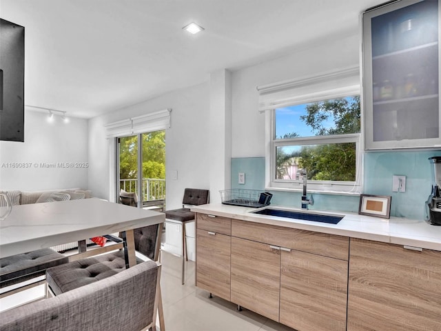 kitchen featuring decorative backsplash, light tile patterned floors, rail lighting, and sink