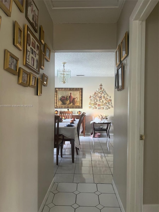hallway featuring a textured ceiling, light tile patterned floors, and a notable chandelier