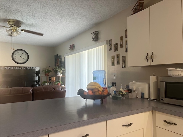 kitchen with white cabinets, a textured ceiling, and ceiling fan