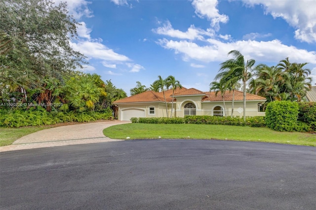 mediterranean / spanish home with a front lawn and a garage