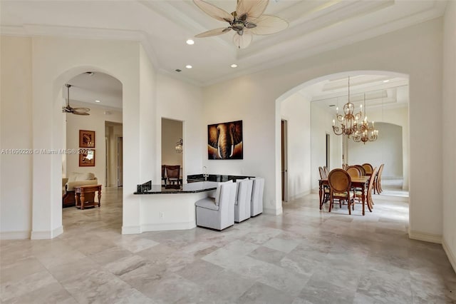 living room with ceiling fan, a high ceiling, a raised ceiling, and ornamental molding