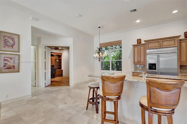 kitchen with decorative backsplash, stainless steel built in refrigerator, a breakfast bar, and light stone countertops