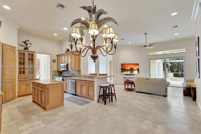 kitchen featuring a kitchen bar, stainless steel appliances, light stone countertops, a kitchen island, and crown molding