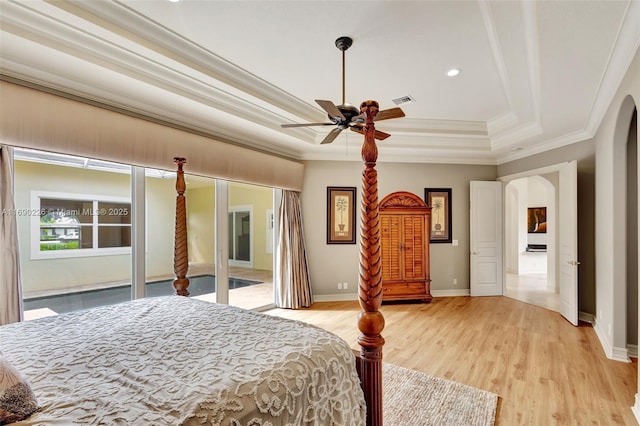 bedroom with ceiling fan, crown molding, a tray ceiling, and light hardwood / wood-style floors