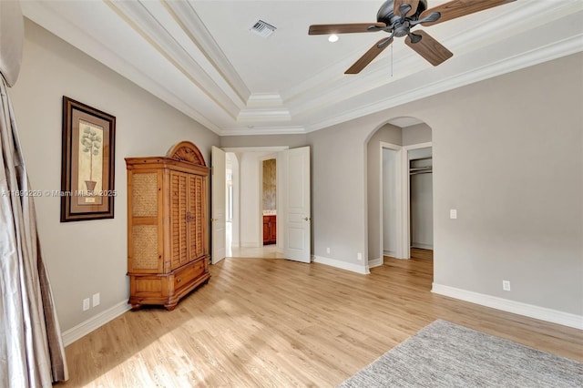 bedroom with ceiling fan, light hardwood / wood-style floors, a raised ceiling, ornamental molding, and a closet