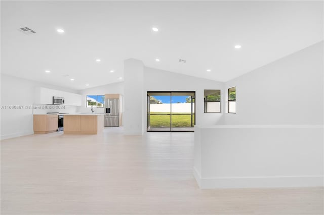 unfurnished living room with sink, light hardwood / wood-style flooring, and vaulted ceiling