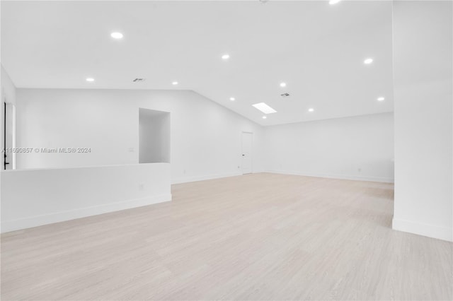 empty room with light wood-type flooring and vaulted ceiling