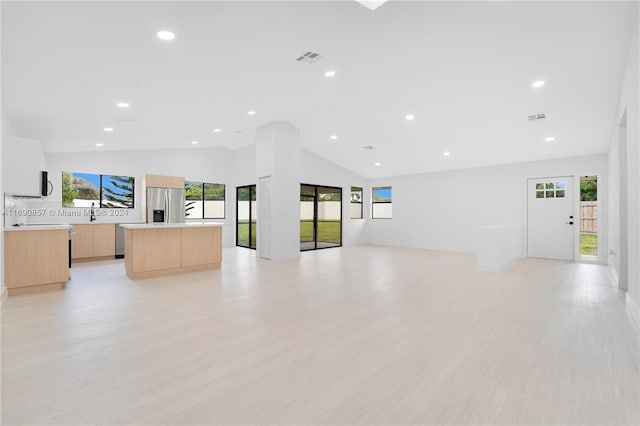 living room with high vaulted ceiling, light wood-type flooring, sink, and plenty of natural light