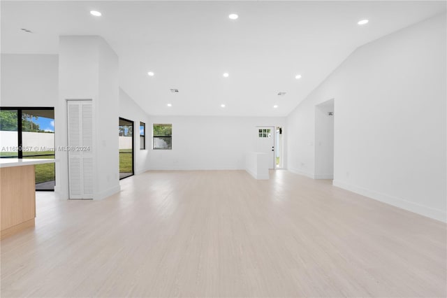 unfurnished living room featuring high vaulted ceiling and light hardwood / wood-style flooring