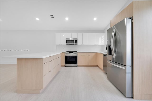 kitchen with stainless steel appliances, white cabinets, tasteful backsplash, light brown cabinets, and light hardwood / wood-style flooring