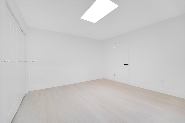 empty room featuring light hardwood / wood-style floors and a skylight