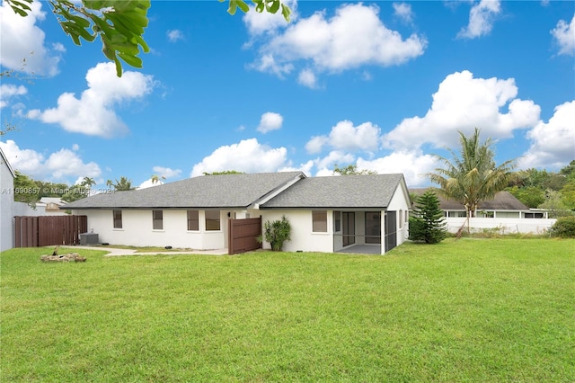 rear view of property featuring central AC, a sunroom, and a lawn