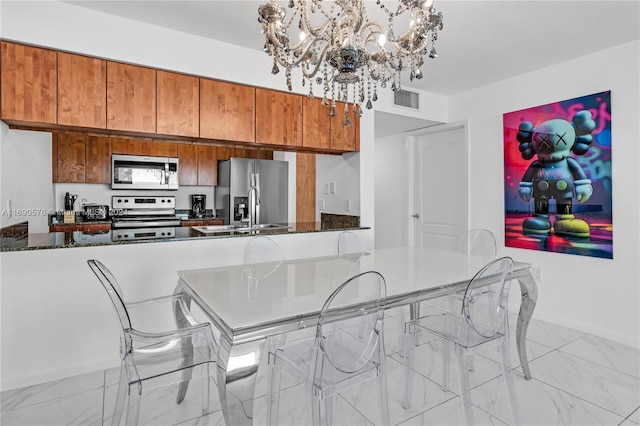 kitchen featuring dark stone counters, kitchen peninsula, a notable chandelier, and stainless steel appliances