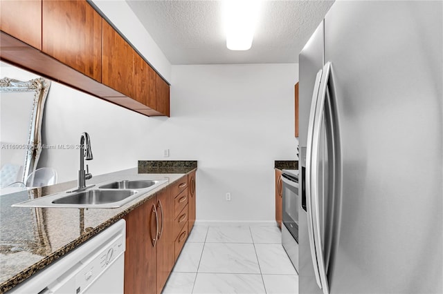 kitchen featuring stainless steel appliances, dark stone countertops, a textured ceiling, and sink