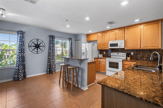 kitchen featuring dark stone counters, sink, white appliances, and a center island