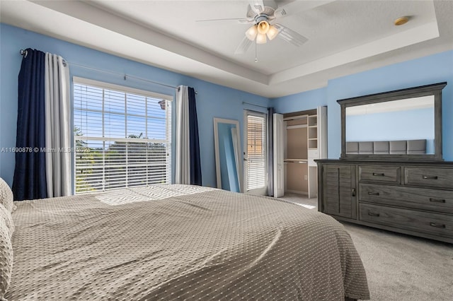 bedroom with ceiling fan, light carpet, and a raised ceiling