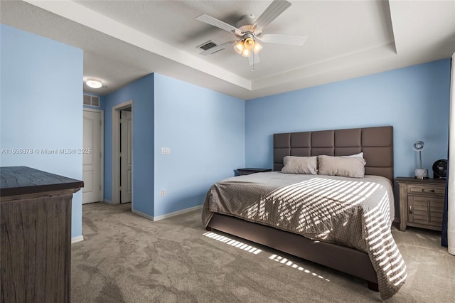 bedroom with ceiling fan, light carpet, and a tray ceiling