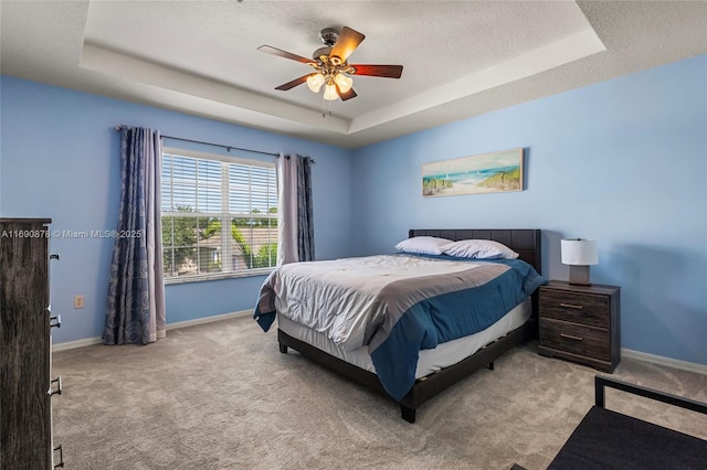 bedroom featuring light carpet, ceiling fan, and a raised ceiling