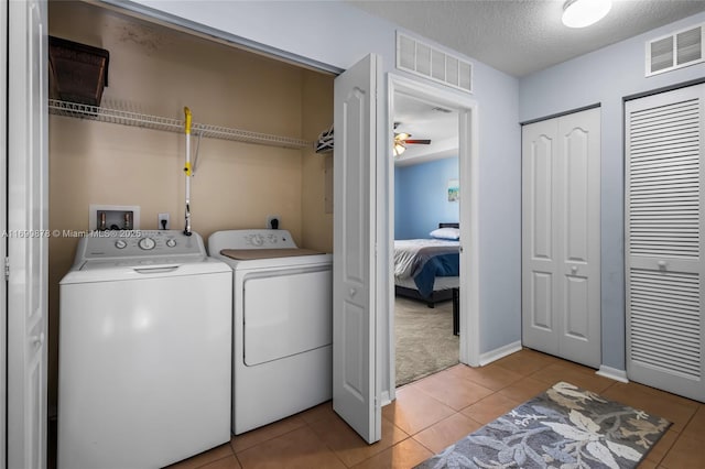 laundry area with light tile patterned flooring, ceiling fan, washer and dryer, and a textured ceiling