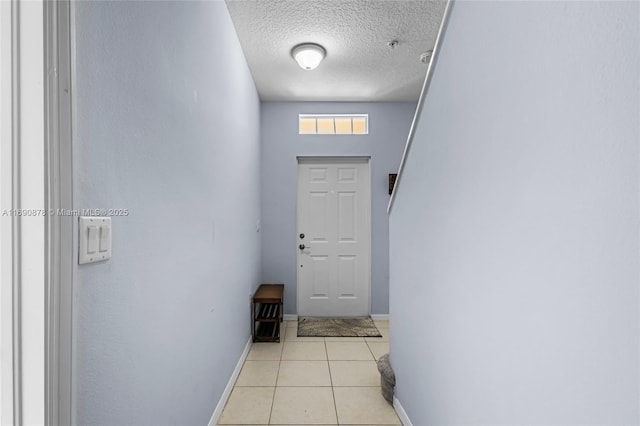 doorway to outside with a textured ceiling and light tile patterned floors