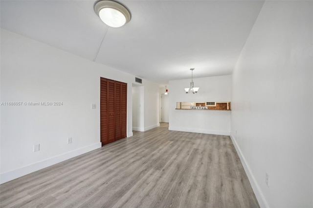 unfurnished living room with light hardwood / wood-style flooring and an inviting chandelier