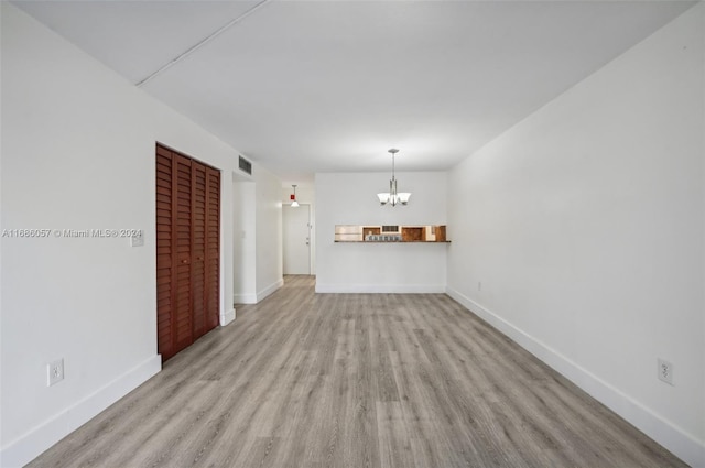 unfurnished living room with light hardwood / wood-style floors and an inviting chandelier