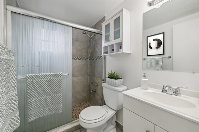 bathroom with toilet, vanity, and a shower with door