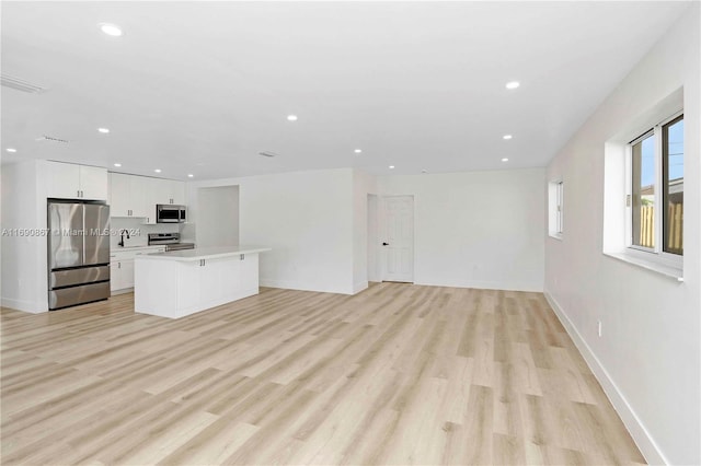 unfurnished living room with sink and light hardwood / wood-style flooring