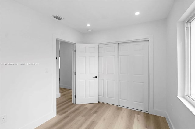 unfurnished bedroom with multiple windows, a closet, and light wood-type flooring