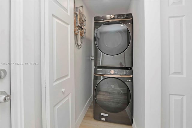 laundry area with stacked washer / drying machine and light hardwood / wood-style floors