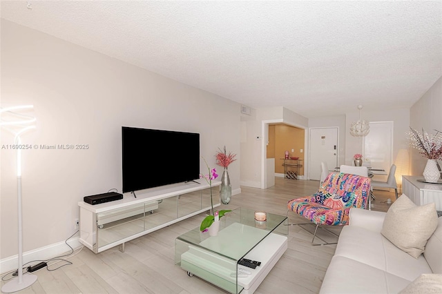 living room with baseboards, a textured ceiling, and wood finished floors