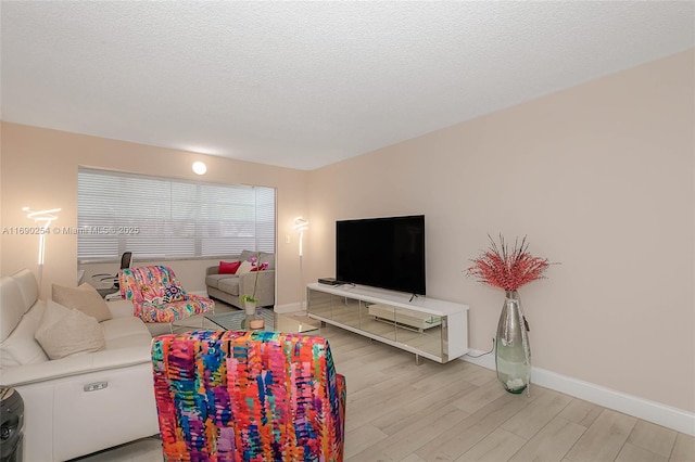 living area with light wood-style flooring, baseboards, and a textured ceiling