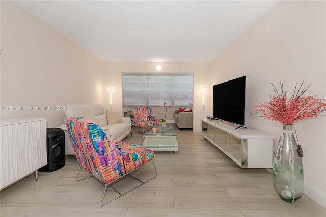 living room with light wood-type flooring, baseboards, and a textured ceiling