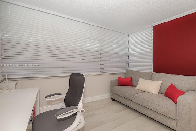 office with light wood-style flooring, baseboards, and a textured ceiling