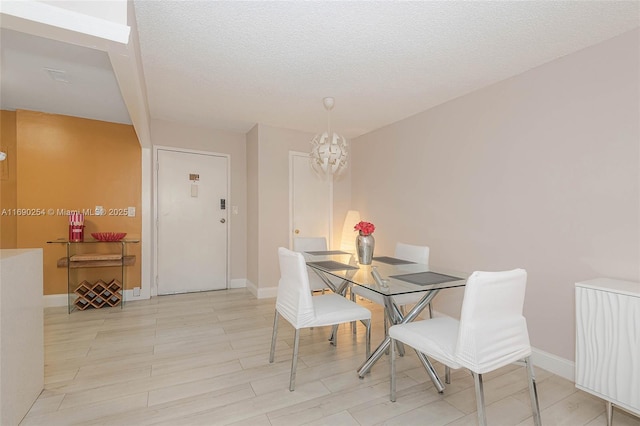 dining room featuring baseboards, a textured ceiling, an inviting chandelier, and wood finished floors