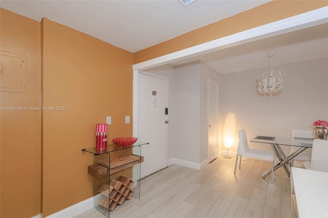 dining space with an inviting chandelier, baseboards, and light wood-type flooring