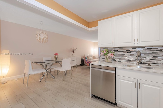 kitchen featuring white cabinetry, light wood-style flooring, a sink, dishwasher, and tasteful backsplash