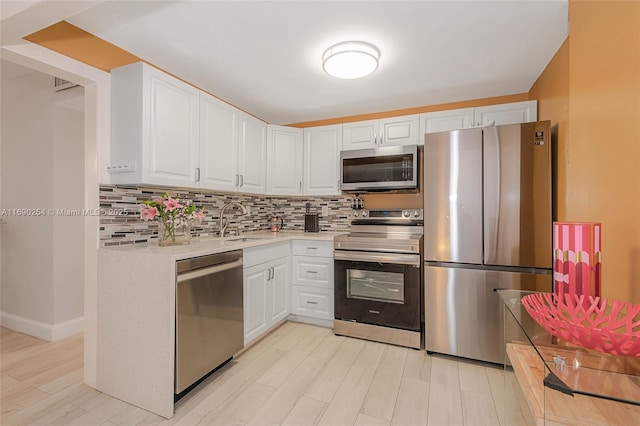 kitchen featuring tasteful backsplash, light countertops, appliances with stainless steel finishes, white cabinets, and a sink