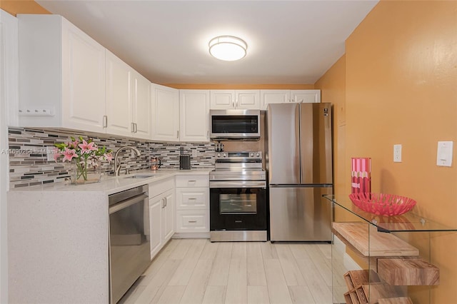 kitchen with decorative backsplash, light countertops, appliances with stainless steel finishes, and a sink