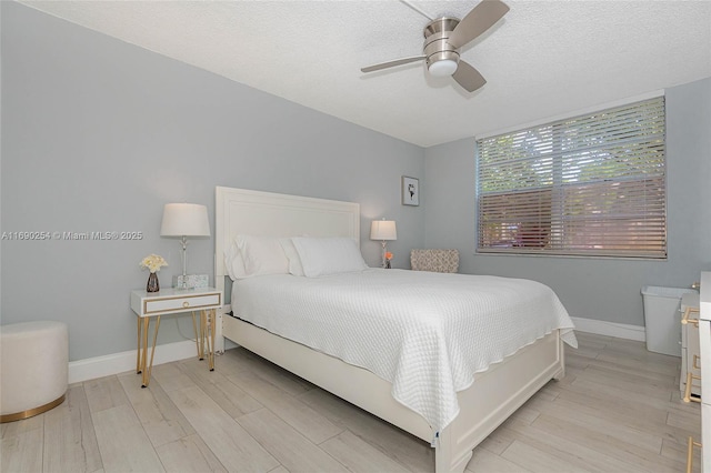 bedroom featuring baseboards, light wood-style floors, and a textured ceiling