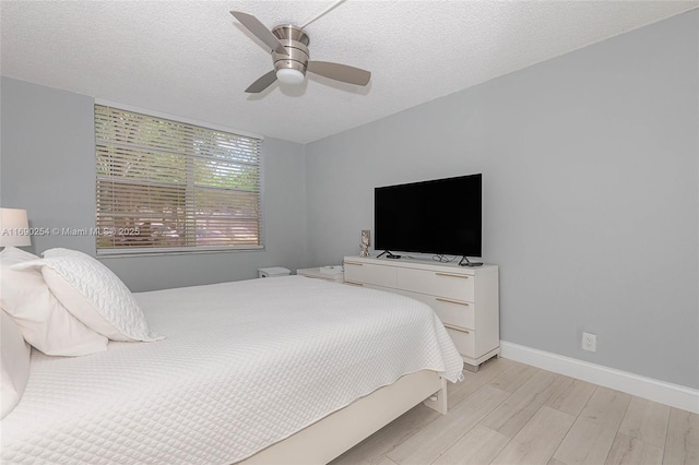 bedroom featuring a ceiling fan, baseboards, light wood-type flooring, and a textured ceiling