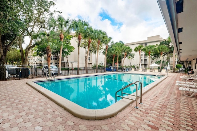 community pool with a patio and fence